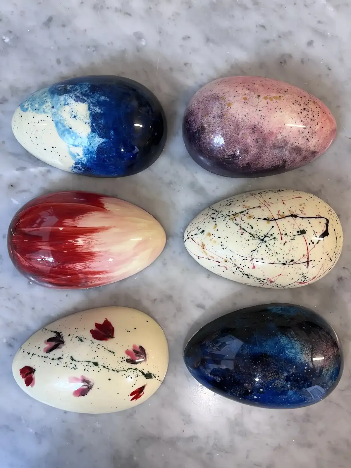 Doppia Sorpresa — six hand-painted Easter eggs in pastel and bold colours on marble